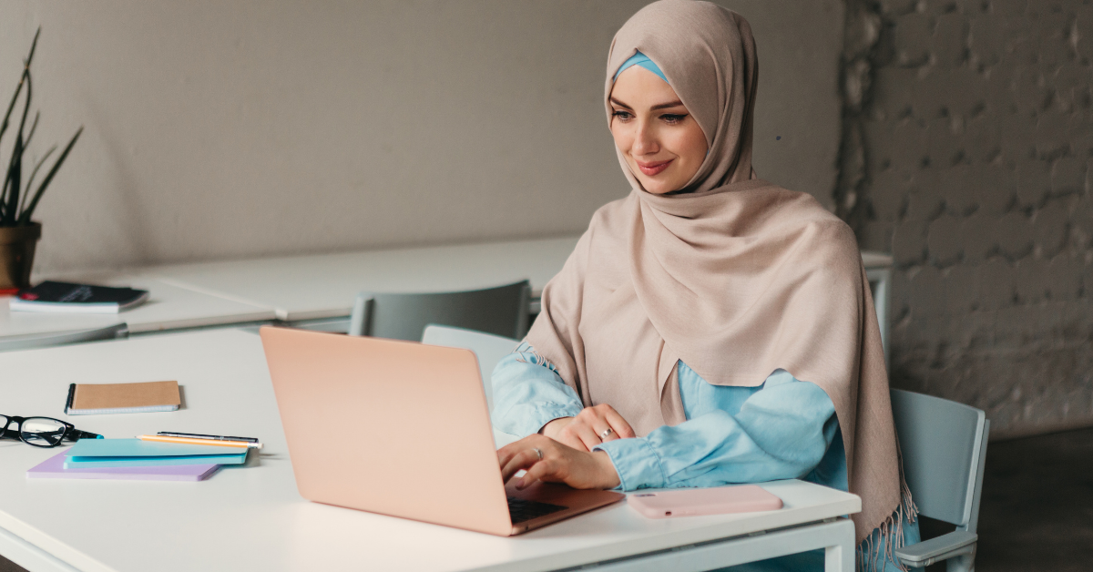 young pretty modern pakistani woman in hijab working on laptop in office room, education online, remote work freelancer, typing thinking concentrated